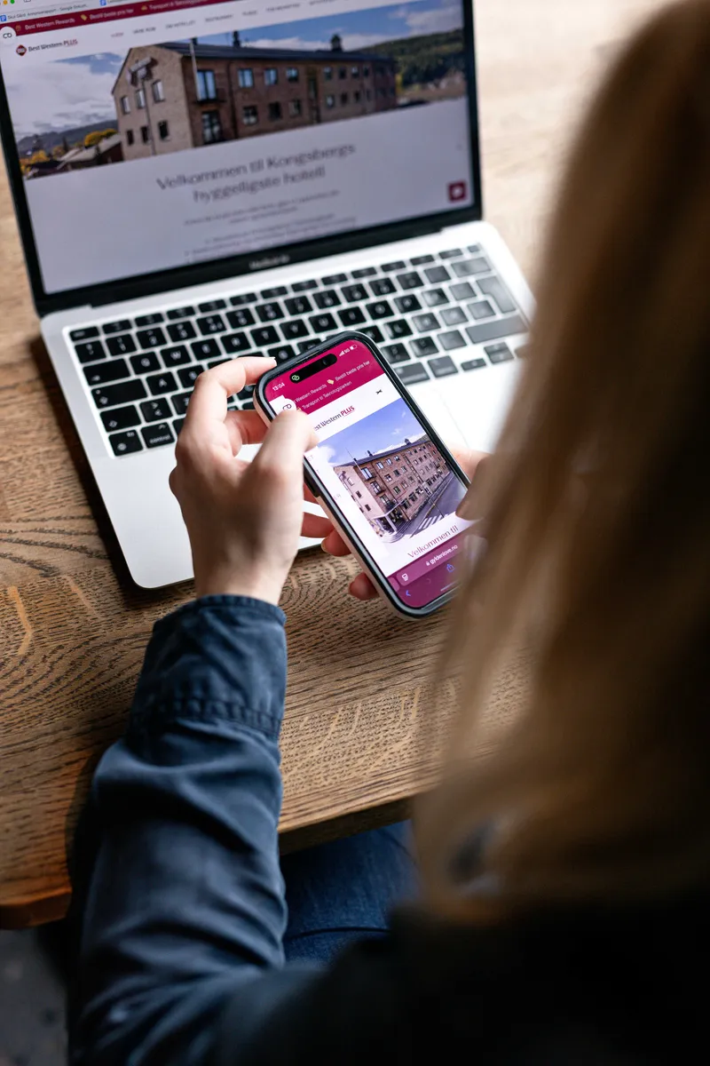 Ansatt jobber med nettside på mobil og laptop