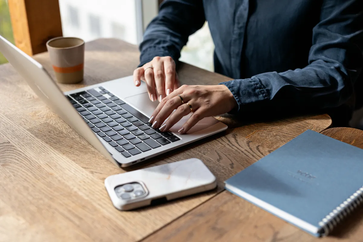 Detalj fra arbeidshverdagen: laptop og notatbok