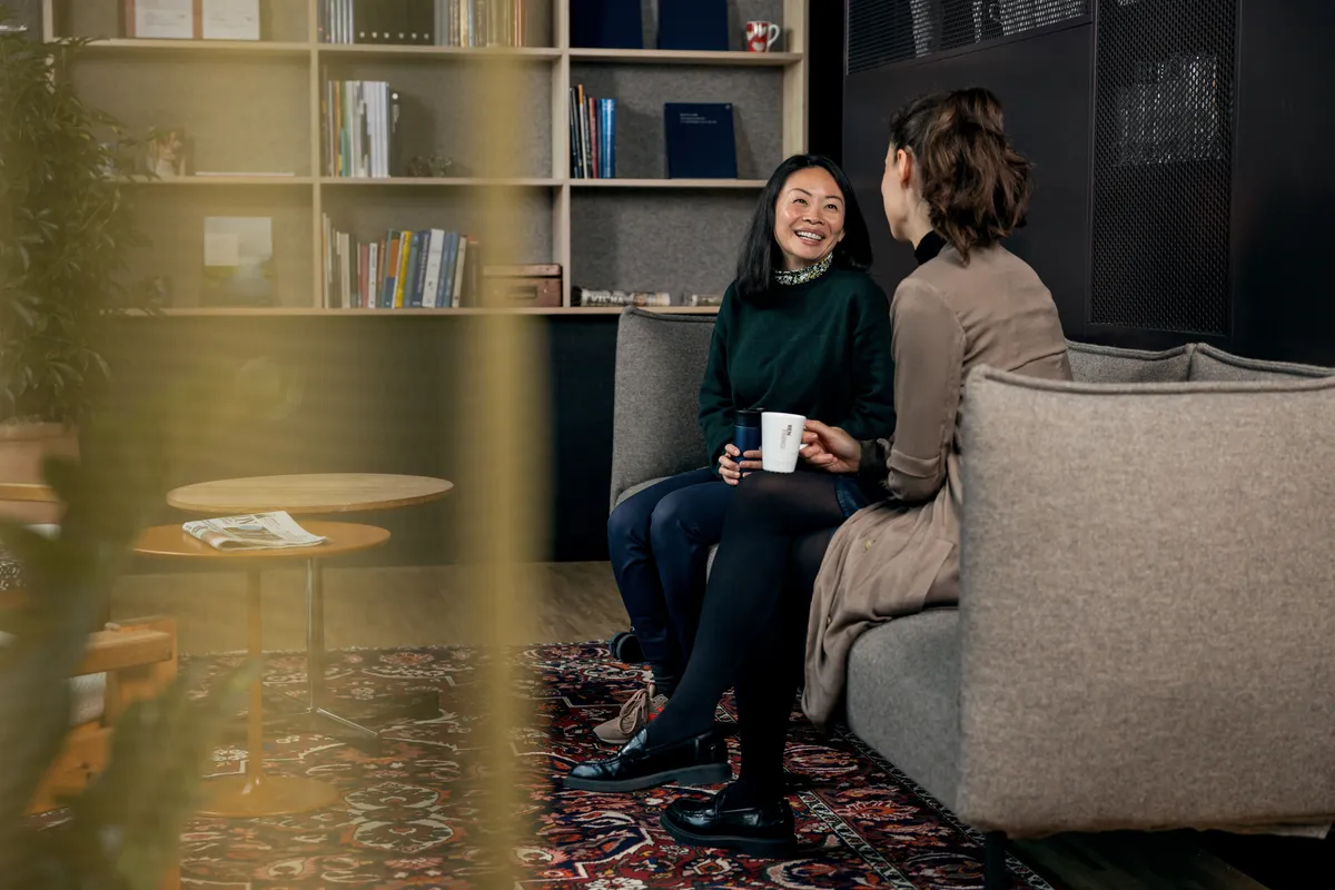 Ansatt sitter og leser i en lun loungesone med bokhylle